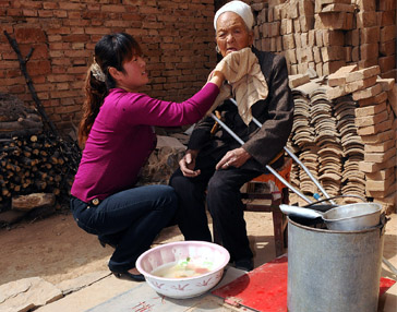 一个修建“母亲水窖”的村庄，一位妇女为妈妈擦脸