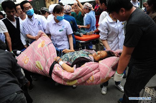 People carry an injured woman to the People's Hospital in the quake-hit Lushan County, southwest China's Sichuan Province, on April 21, 2013. Military and civilian rescue teams are struggling to reach every household in Lushan and neighboring counties of southwest China's Sichuan Province, badly hit by Saturday's strong earthquake. [Xinhua]